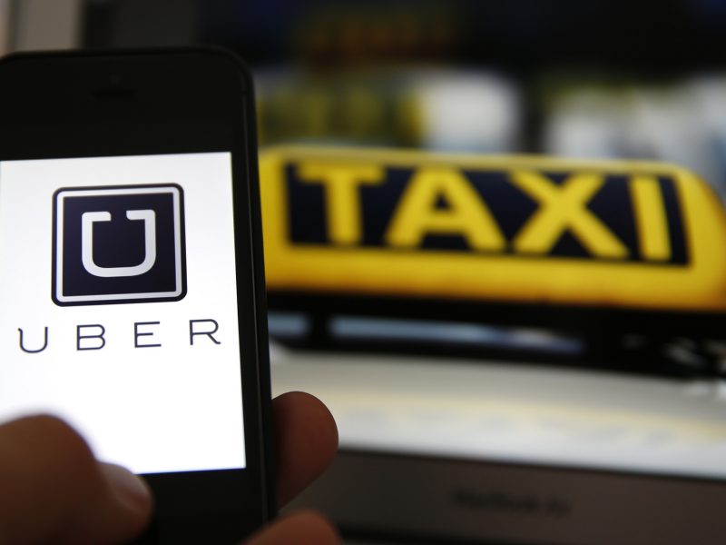 File illustration picture showing the logo of car-sharing service app Uber on a smartphone next to the picture of an official German taxi sign in Frankfurt, September 15, 2014. A Frankfurt court earlier this month instituted a temporary injunction against Uber from offering car-sharing services across Germany. San Francisco-based Uber, which allows users to summon taxi-like services on their smartphones, offers two main services, Uber, its classic low-cost, limousine pick-up service, and Uberpop, a newer ride-sharing service, which connects private drivers to passengers - an established practice in Germany that nonetheless operates in a legal grey area of rules governing commercial transportation.    REUTERS/Kai Pfaffenbach/Files  (GERMANY - Tags: BUSINESS EMPLOYMENT CRIME LAW TRANSPORT)